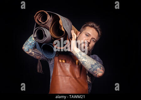 Craftsman working with leather creates a new leatherwork in the studio. Stock Photo