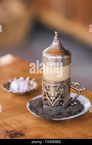 Traditional turkish coffee served in beautiful metal cup on hot sand and turkish delights at background in outdoor cafe in Turkey Stock Photo