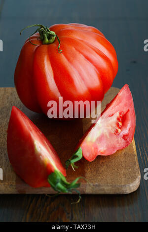 Large freshly harvested whole and sliced oxheart tomatoes. Dark wooden table, high resolution Stock Photo