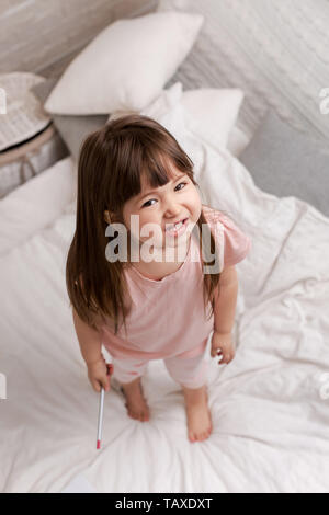 happy smiling little child girl in pyjamas in bed. Stock Photo