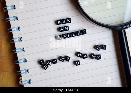 Ask an Expert on wooden block and magnifying glass. Motivation concept Stock Photo