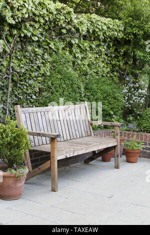 Traditional wooden garden bench on a patio in an English garden Stock Photo