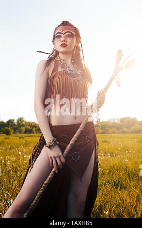 Outdoor portrait of the pretty young shamaness (witch doctor) with staff. Lovely shaman (sorceress) in the field Stock Photo