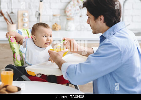 Dad feeding his baby with healthy food Stock Photo