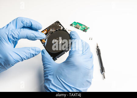 Visual inspection of an opened hard disk with gloves Stock Photo