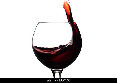 Red wine splash into glass on white background. Stock Photo