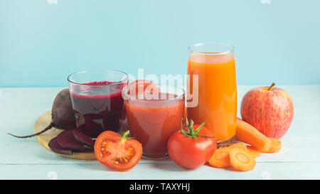 Fresh juice smoothies from a variety of vegetables beetroot apple carrot tomatoes in glasses on wooden blue background. Stock Photo