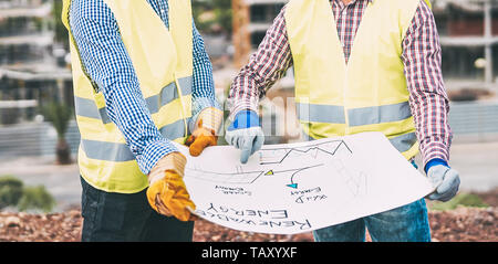 Workers engineers discussing about the new building area - Young builders reading the project in the construction site Stock Photo