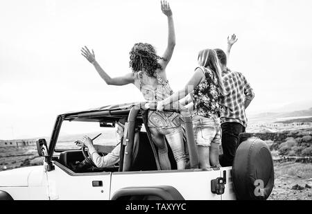 Group of friends driving off road convertible car during roadtrip - Happy travel people having fun in vacation Stock Photo
