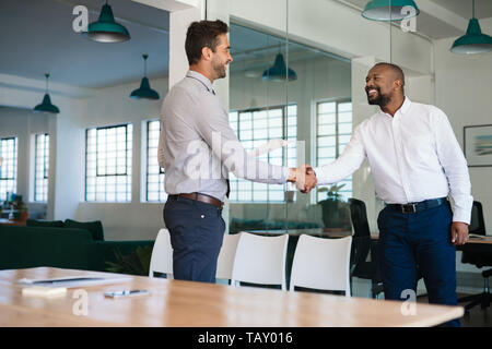 Smiling manager congratulating and shaking hands with a job applicant after a successful interview Stock Photo