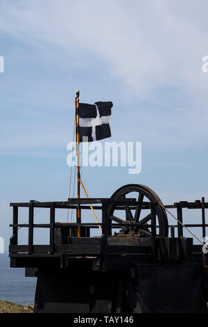 St Piran's Flag, the flag of Cornwall flying from the top of the winding gear at the old Levant tin mine on the Cornish Tin coast in England Stock Photo