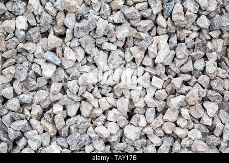 Closeup of small little grey beige blue broken crushed stones rocks lying on ground. Natural environmental background texture. Garden rubble macadam t Stock Photo
