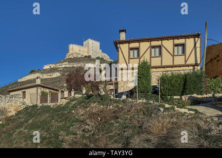 Typical house of the village of Curiel de Duero with the castle on the rocky hill in the background in the province of Valladolid, Castilla y León, Sp Stock Photo