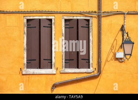 Photograph taken of two brown closed window shutters in the medieval water town of Venice, Italy. Stock Photo
