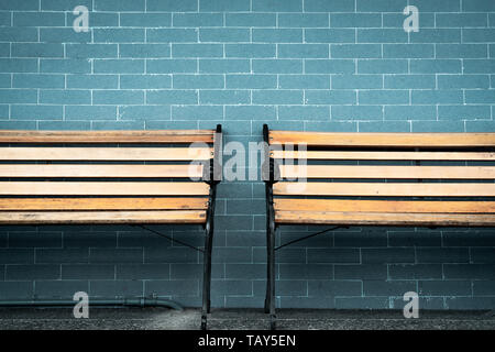 Empty two wooden bench on green brick wall background. Waiting for someone to full fill empty wooden chair. Brown wooden bench outside the building. Stock Photo