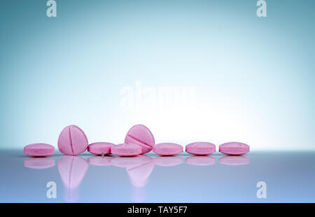 Pink tablets pills with shadow on gradient background. Pharmaceutical industry. Pharmacy products. Vitamins and supplements. Medication use Stock Photo