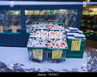 Snow covered crates of apples, oranges and grapes outside a greengrocers shop in Oslo Norway in the winter Stock Photo