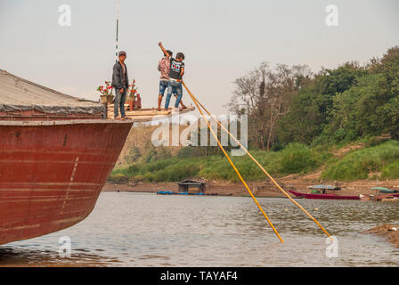 Nakaraj Nakhon, Laos - Feb 2016: Laotians pushing the ship with big poles over the Mekong river Stock Photo