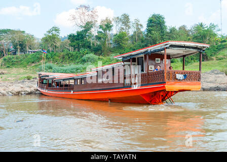 Nakaraj Nakhon, Laos - Feb 2016: Couple sitting at the back of Laotian longboat waiting for the tourist to start the ride on Mekong river Stock Photo