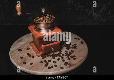 Old wooden coffee grinder and coffee beans on concrete background. Stock Photo
