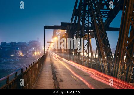 Traffic on Long Bien Bridge against cityscape. Hanoi at night, Vietnam. Stock Photo