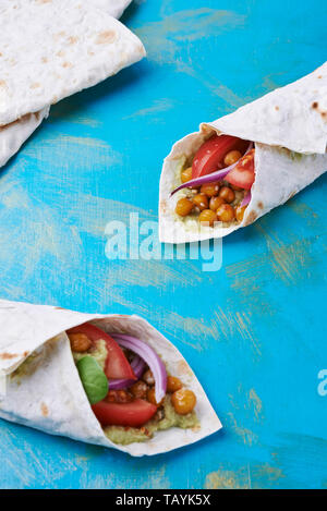 Vegan wraps in pita with chickpeas and mashed avocado on blue background Stock Photo
