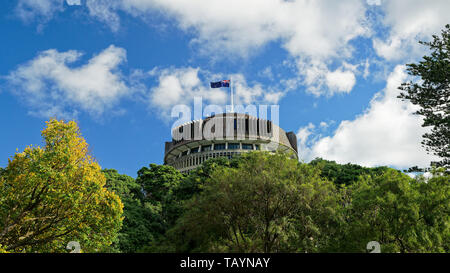 The Beehive above the treeline - New Zealand parliament building with flag flying on a sunny day Stock Photo