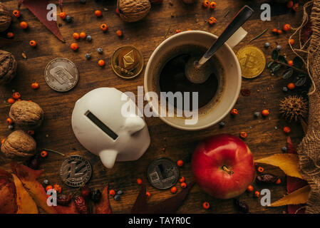 Piggy coin bank and cryptocurrency coins on table with autumn season edcoration arrangement, top view flay lay retro toned digital wallet concept Stock Photo