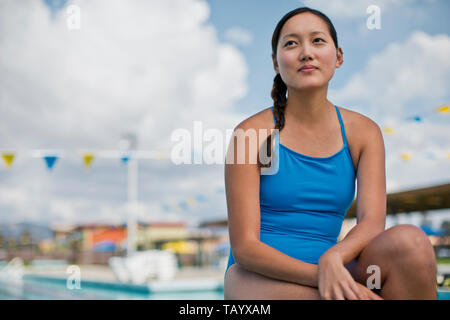 Young woman sitting poolside in her swimsuit. Stock Photo
