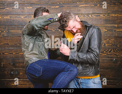 Street fight concept. Men brutal hooligans wear leather jackets fighting. Physical attack. Men bearded hipster fighting. Attack and defence. Aggressive hooligan fighting with strong bully man. Stock Photo