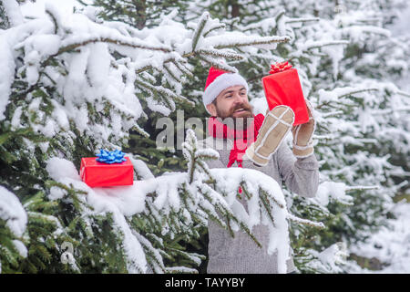 Happy holiday and xmas. Boxing day, party celebration. Bearded man in santa hat at new year. Christmas happy man with beard hold present box. Hipster  Stock Photo