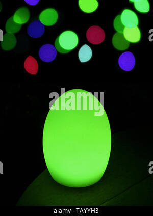 Shining neon green egg shaped table lamp with vibrant bokeh in background Stock Photo