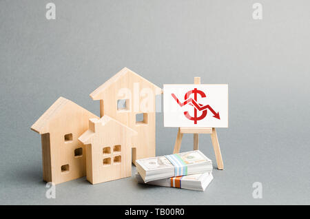 Wooden figures of houses and a poster with a symbol of falling value. concept of real estate value decrease. low liquidity and attractiveness of asset Stock Photo