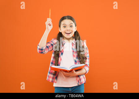 That book has given me several ideas. Little girl writing down her idea into diary. Small child pointing pen up having genius idea. Adorable schoolgirl got main idea of book. Stock Photo
