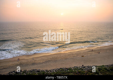 View from above, stunning aerial view of a beautiful tropical beach with people sunbathing and enjoying a beautiful sunset. Varkala, Kerala, India. Stock Photo