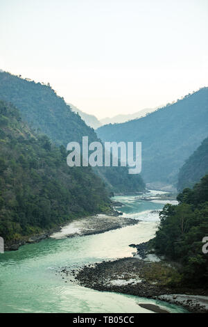 Stunning view of some green mountain peaks with the Sacred Ganges River flowing between them in Rishikesh, India. Stock Photo