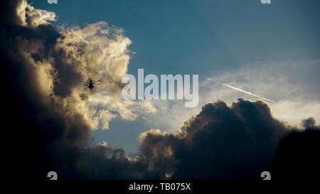 Silhouette of helicopter in flight against dramatic sky and clouds Stock Photo