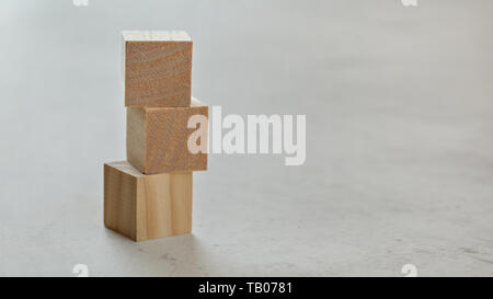Pile with three empty wooden cubes - add your letters, on white board, space for text on right. Stock Photo