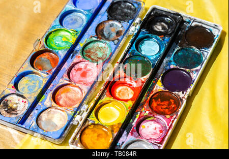 Different used colorful watercolor paint on a yellow background Stock Photo