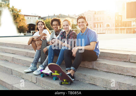 Teen friends company sitting outdoor, spending summer together Stock Photo