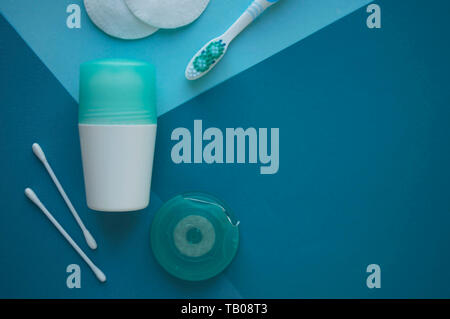 A deodorant, cotton pads for face and buds for ears, toothbrush and dental floss on blue background of different tones. Health care. Beauty concept. Stock Photo