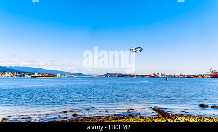Float plane taking off from the Vancouver Harbor. Viewed from the Stanley Park Seawall pathway with the Second Narrows Bridge in the background in BC Stock Photo