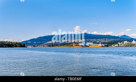 View of the North Shore of the Vancouver Harbor with Grouse Mountain in the background. Viewed from the Stanley Park Seawall pathway in BC, Canada Stock Photo