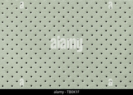 Perforated green leather texture background, closeup. Light olive backdrop from wrinkle skin, structure of textile. Stock Photo