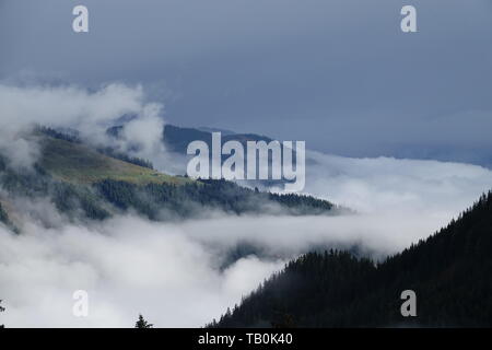 a morning in the mountains with fog in the valley and cloudy sky Stock Photo