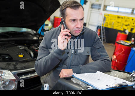 mechanic using a phone in auto shop Stock Photo