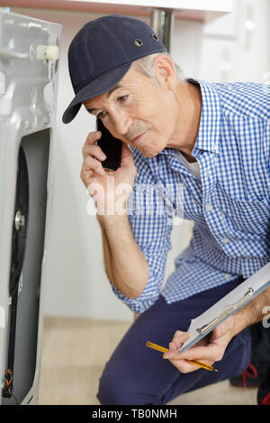 male technician on the phone checking a machine Stock Photo