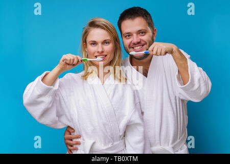 Photo of woman and man and toothbrushes in hands on empty blue background Stock Photo