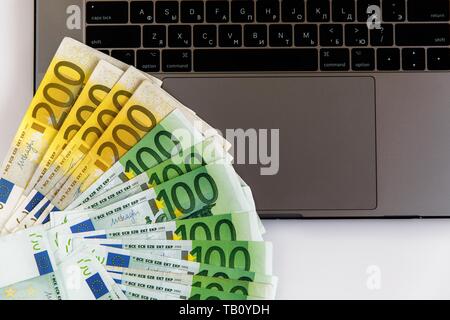 Banknotes of different denominations lie near the laptop Stock Photo