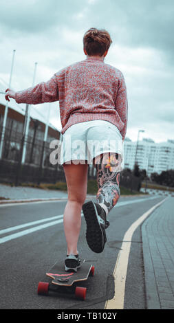Beautiful young girl with tattoos with longboard in the town. She has traditional japanese tattoo Stock Photo